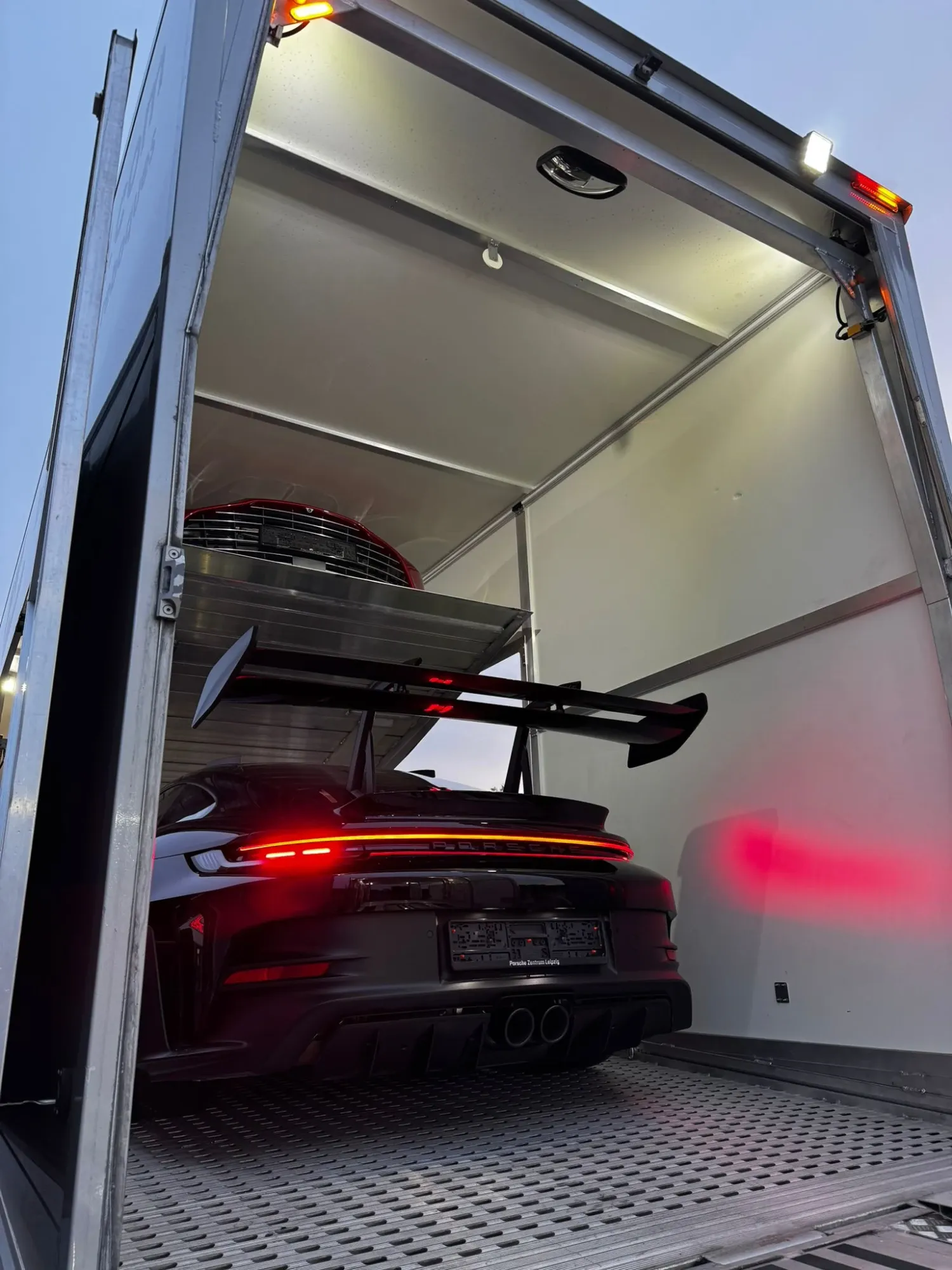 Porsche 911 GT3 RS vastgezet in de gesloten trailer, met een tweede auto op de bovenste laadvloer
